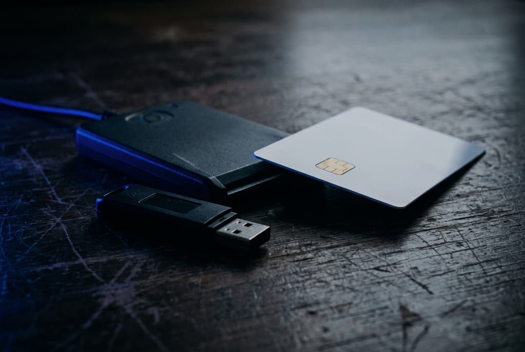 Lettore di smart card e chiavetta di firma digitale su un tavolo scuro