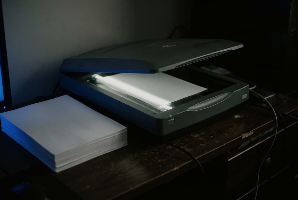 Scanner in funzione su una pila di documenti, luce blu radente in penombra